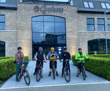 Group of mountain bikers riding eMTBs together on a forest trail, wearing helmets and cycling gear, representing Cycle 360 and Enduro Isle’s upcoming social eMTB ride.